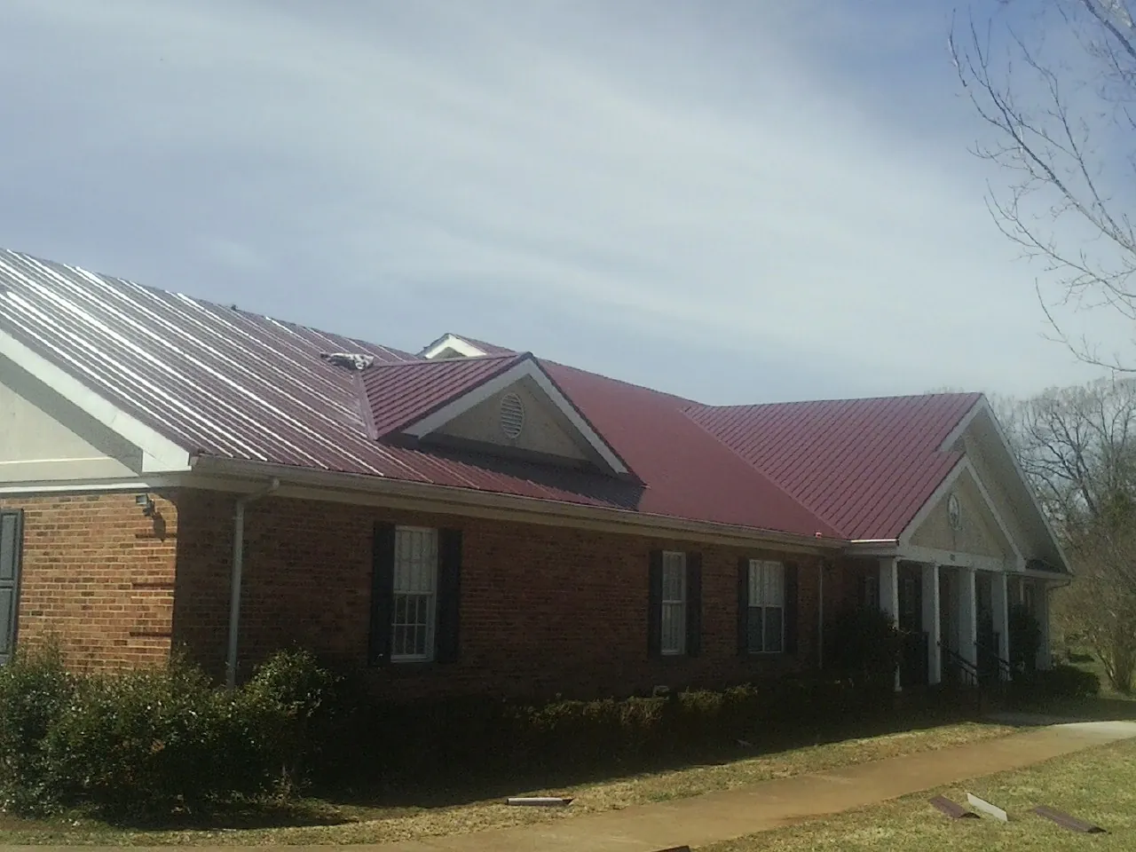 Red metal roof with gabled entries on a long brick building in Shawnee